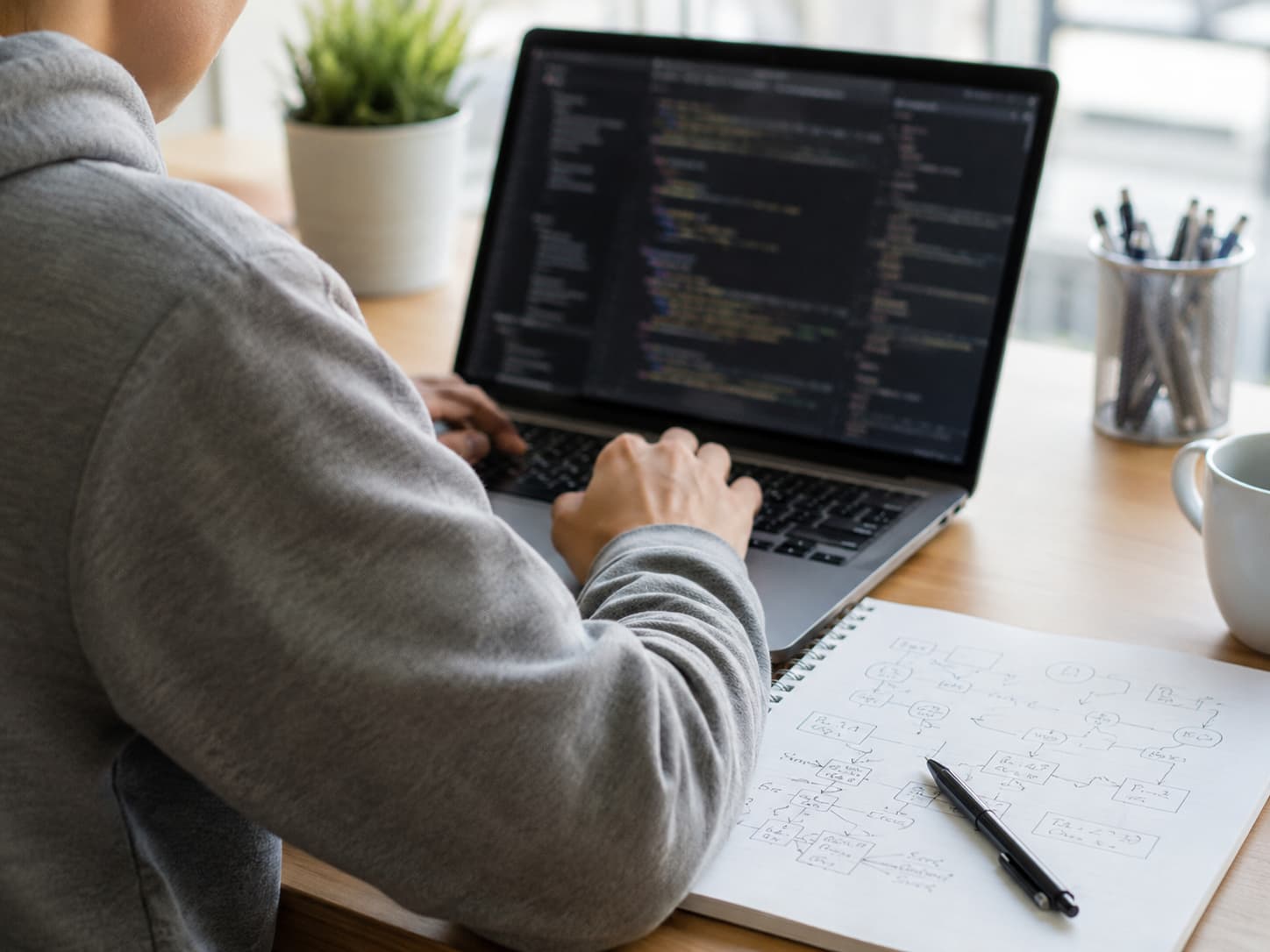 Alumno aprendiendo programación con código en un portátil y apuntes de lógica